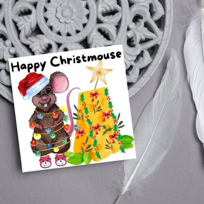 Square Christmas card featuring a cartoon mouse wrapped in christmas lights and wearing a santa hat and slippers next to a christmas tree made from cheese with decorations of holly and red bows. The text, Happy Christmouse is written at the top