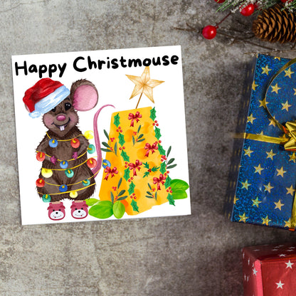 Square Christmas card featuring a cartoon mouse wrapped in christmas lights and wearing a santa hat and slippers next to a christmas tree made from cheese with decorations of holly and red bows. The text, Happy Christmouse is written at the top