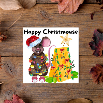 Square Christmas card featuring a cartoon mouse wrapped in christmas lights and wearing a santa hat and slippers next to a christmas tree made from cheese with decorations of holly and red bows. The text, Happy Christmouse is written at the top