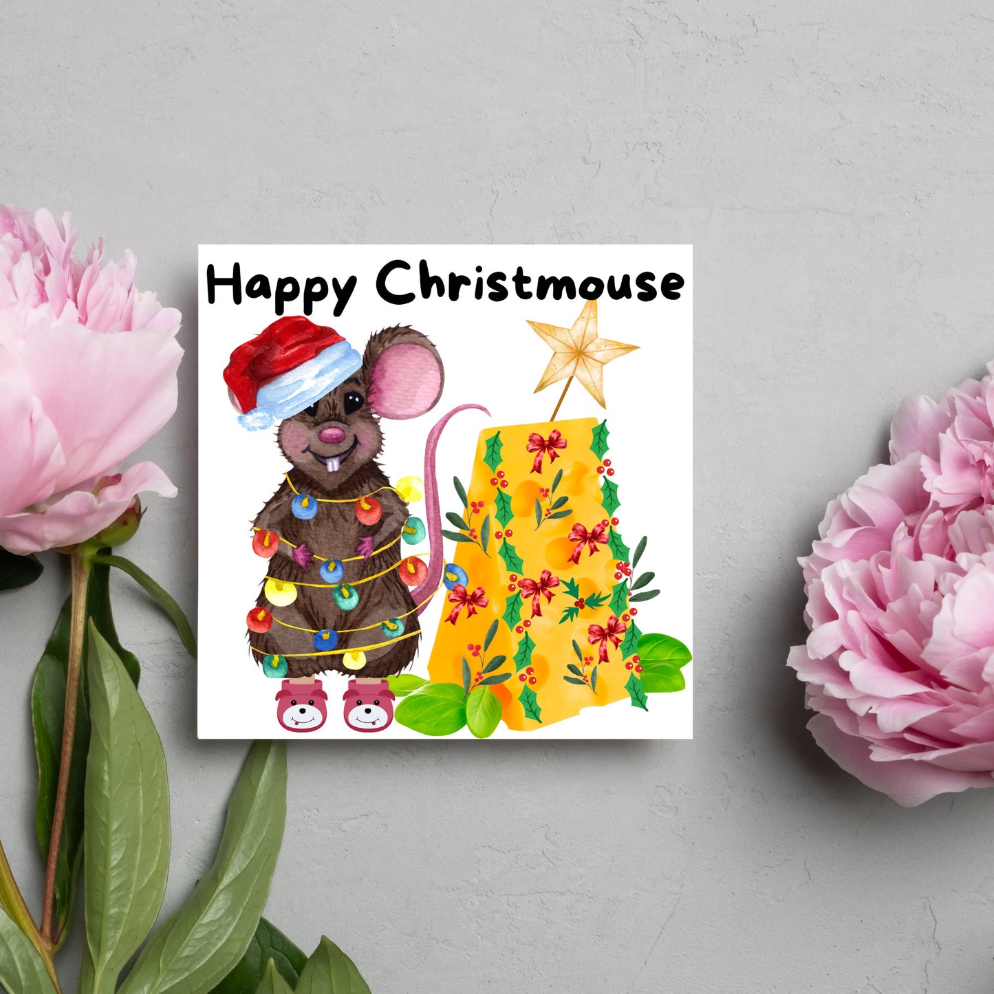 Square Christmas card featuring a cartoon mouse wrapped in christmas lights and wearing a santa hat and slippers next to a christmas tree made from cheese with decorations of holly and red bows. The text, Happy Christmouse is written at the top