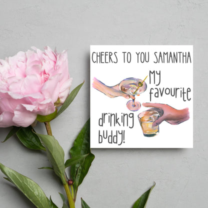 Square card with watercolour design of 2 hands holding drinks glasses against a white background, with grey text that reads &quot;cheers to you Samantha, my favourite drinking buddy&quot;