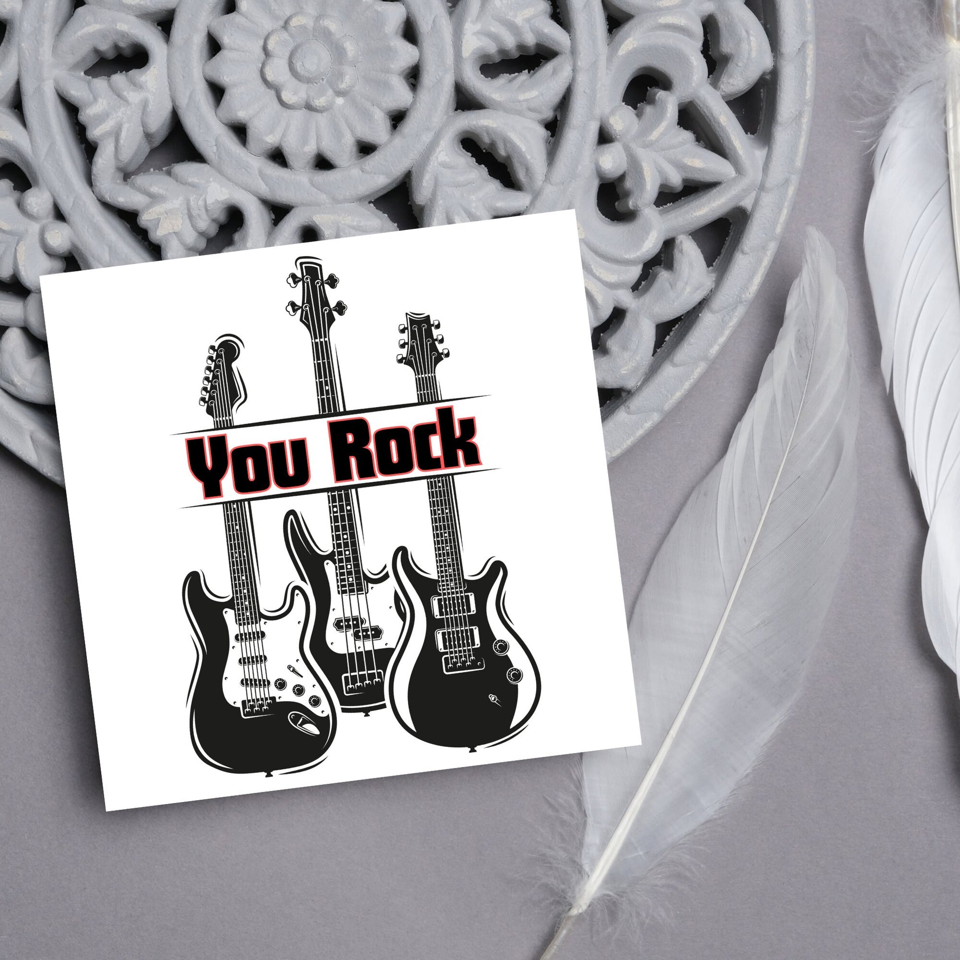 Square Greetings card featuring 3 black electric guitars with &#39;you rock&#39; written across them in red and black