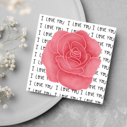 simple elegant card for valentines or anniversary, featuring a large pink rose  painting with a background of handwritten style text that repeats &#39;I love you&#39; with hearts instead of o&#39;s