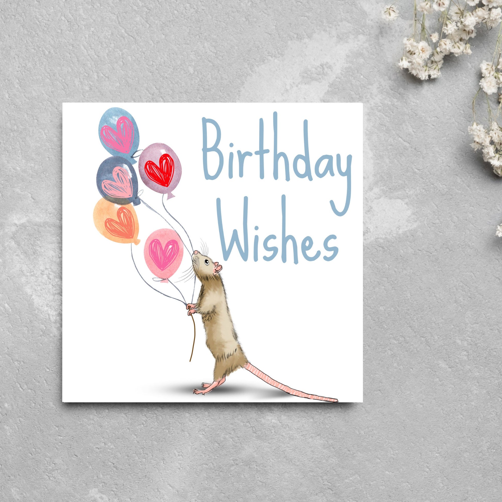 This square card features an illistration of a small mouse/rat holding some balloons with love hearts in a cute cartoon design. The card is captioned Birthday Wishes in a blue handwritten font. The design is on a white background