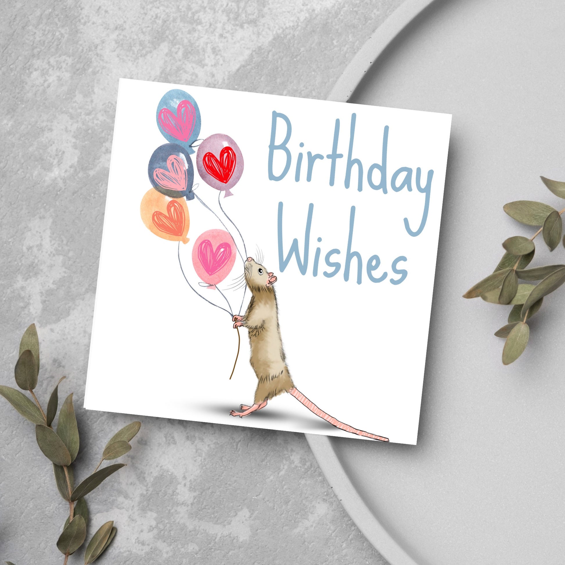 This square card features an illistration of a small mouse/rat holding some balloons with love hearts in a cute cartoon design. The card is captioned Birthday Wishes in a blue handwritten font. The design is on a white background