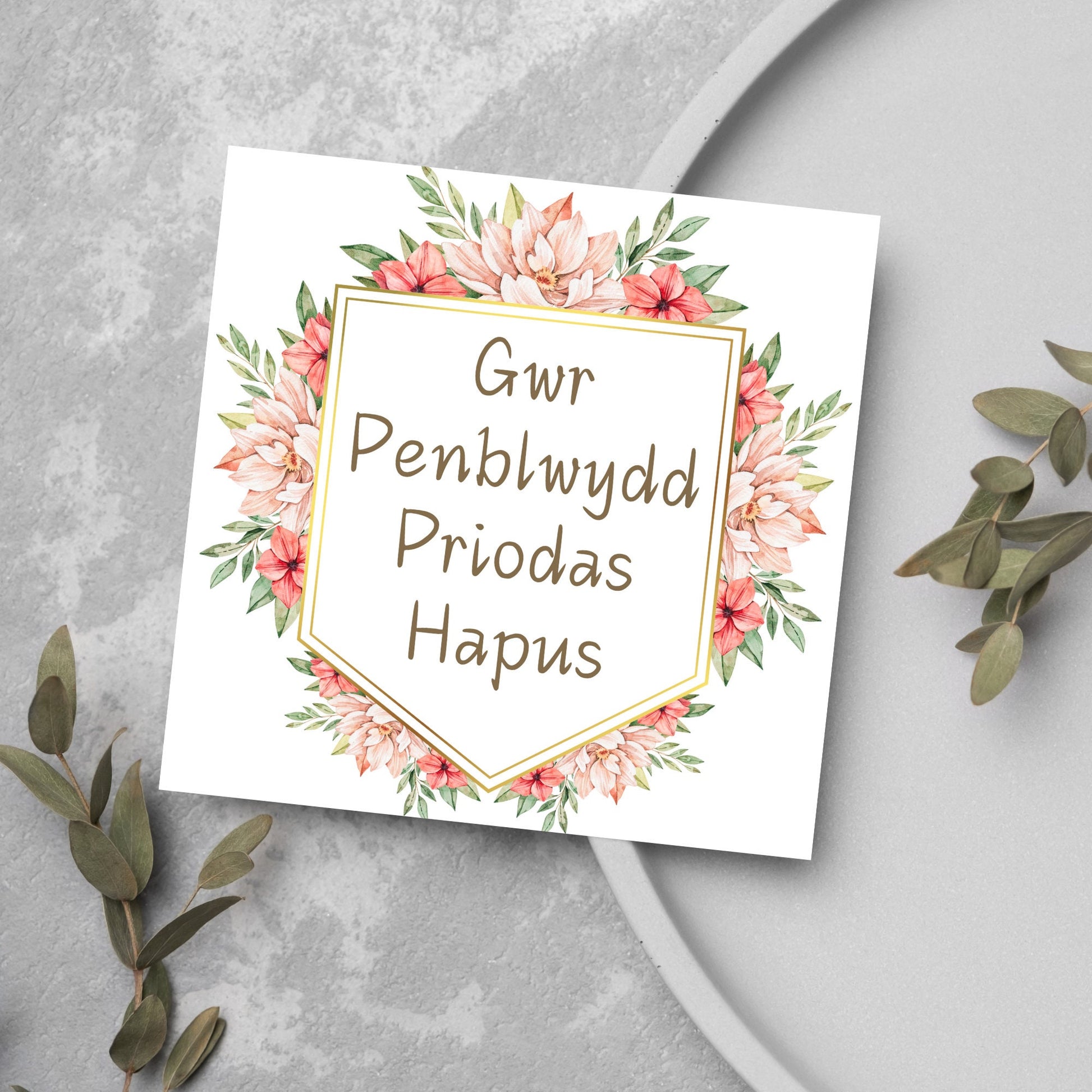 Image of a square wedding anniversary card with &#39;gwr penblwydd priodas hapus&#39; in a subtle handwritten style font, which translates to &#39;happy wedding anniversary&#39; in welsh. the text is against a white banner surrounded by pink flowers