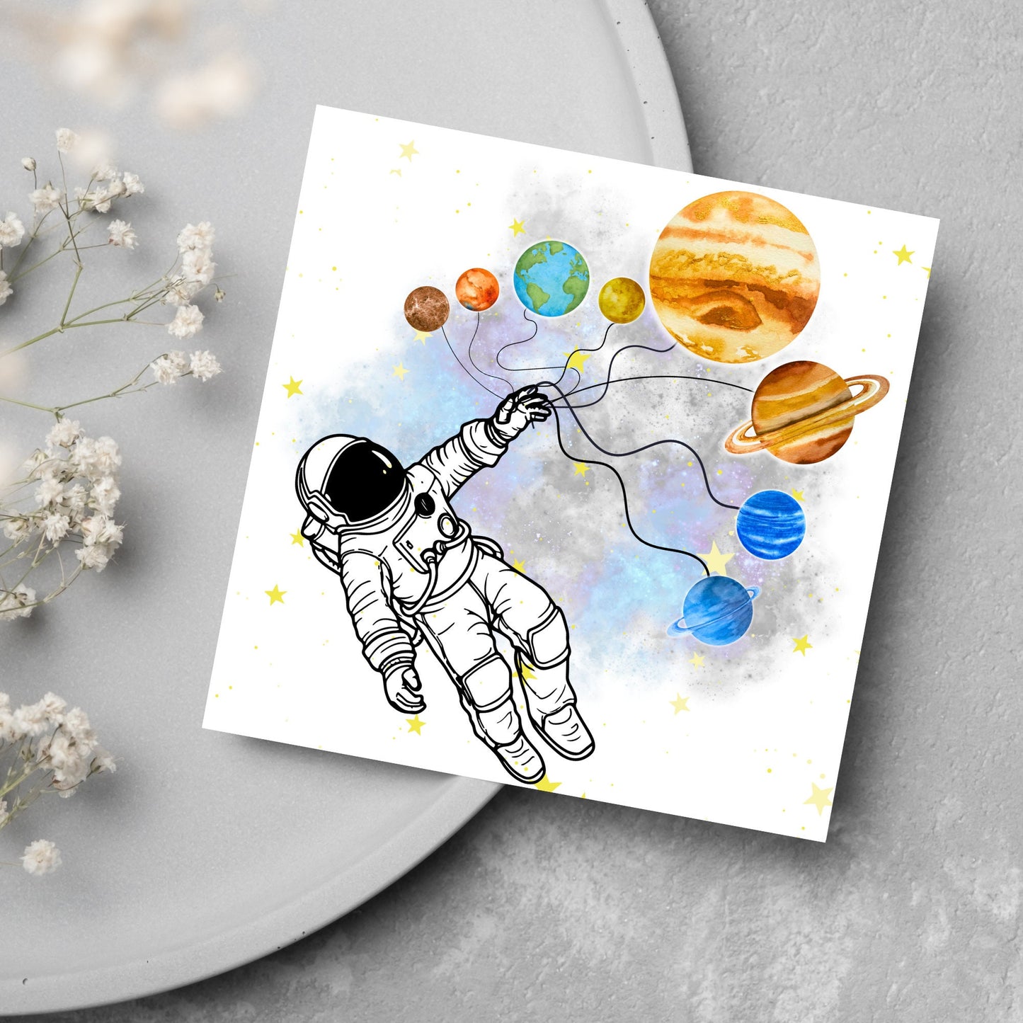 This square shaped card has an illustration of an astronauts holding the planets of the milky way in a watercolour inspired design. There is a collection of yellow stars and a watercolour nebula in the background