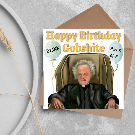 square birthday card with a hand drawn image of father jack from the tv show father ted. he is sitting in his chair looking mean with the text happy birthday gobshite above him. 2 balloons are next to him with feck off and drink on them