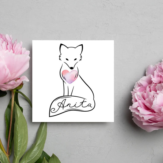 Square card with simple black line drawing of a fox  sitting with its tail wrapped around its feet. It has a pink watercolour heart on its chest and personalised with a name on the tail in a calligraphy font