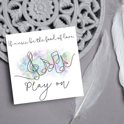 White square card with a one line drawing of musical notes that look like they are dancing in front of a pastel rainbow watercolour cloud. Cursive text reads, If music be the food of love, play on