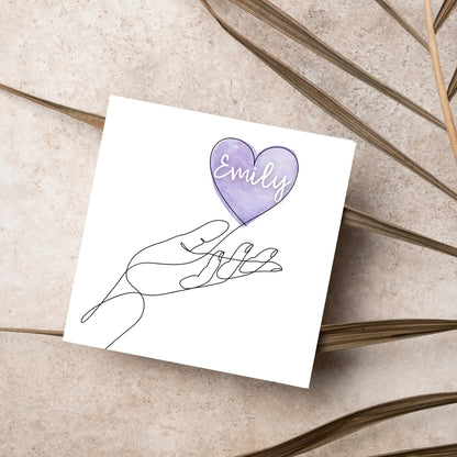 square card with a simple black and white one line drawing of an open hand with a heart rising from the hand. the heart has a purple background and has a personalised name written in a white cursive text