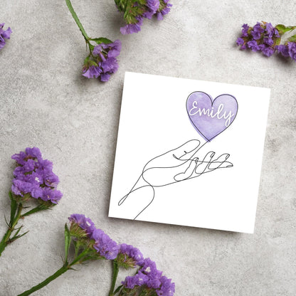 square card with a simple black and white one line drawing of an open hand with a heart rising from the hand. the heart has a purple background and has a personalised name written in a white cursive text