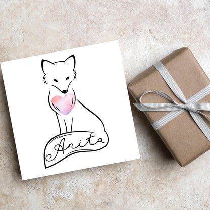 Square card with simple black line drawing of a fox  sitting with its tail wrapped around its feet. It has a pink watercolour heart on its chest and personalised with a name on the tail in a calligraphy font