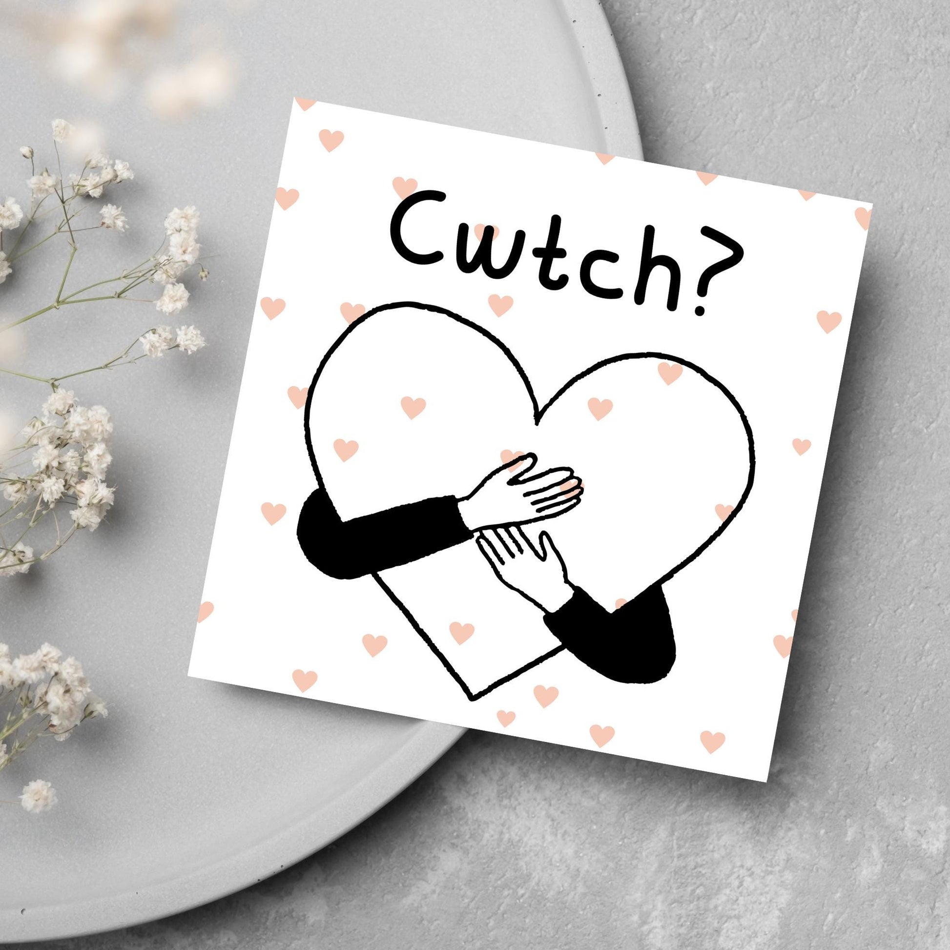 Square Greeting card small with subtle pink hearts in the background of a line drawn heart with hands hugging it and the word CWTCH? above it in handwritten style text