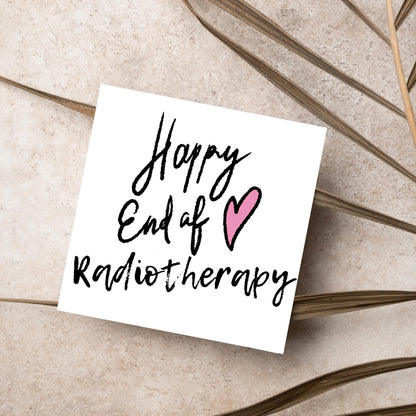 Simple square card with a white backdrop and black handwritten style text that reads HAPPY END OF RADIOTHERAPY with a roughly drawn pink heart next to the text.