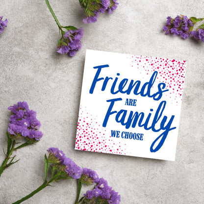 Square card with small hearts on opposite corners in shades of pink and blue writing in the centre that reads Friends are Family we choose
