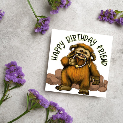This square shaped card has an illustration of Ludo from the 80s Bowie film Labyrinth. Ludo towers over some rocks and has a door knocker in their mouth. The caption reads Happy Birthday Friend, this text arches above Ludo. This card is perfect for any fans of the film Labyrinth