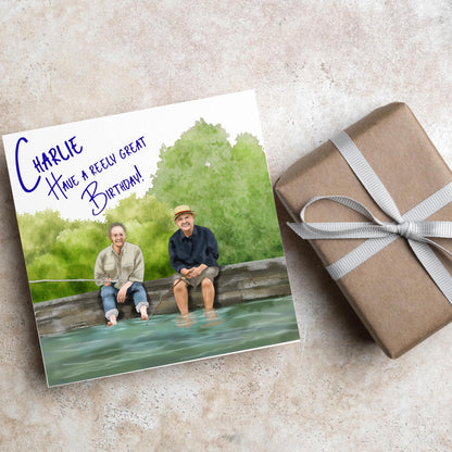 square greetings card with a hand drawn image of bob Mortimer and paul Whitehouse sitting on the edge of a dock fishing with their bare feet in the water. behind them are watercolour trees and bushes and blue text that reads &#39;charlie, have a freely great birthday&#39; in a handwritten style font