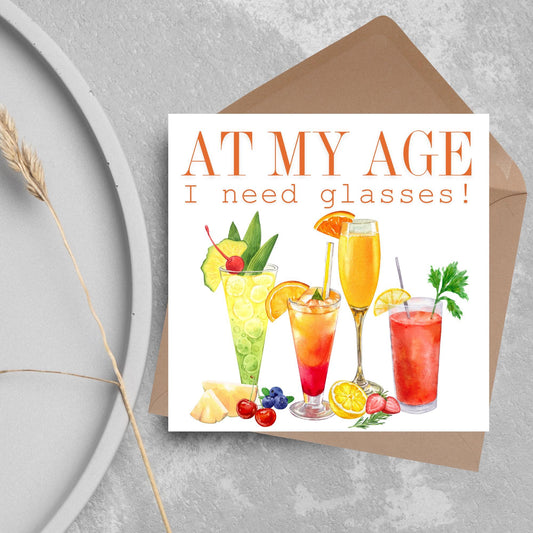 Image of a square birthday card with colourful illustrations of cocktails with the text - at my age I need glasses!